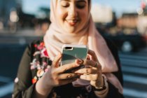 Jovem mulher no hijab olhando para o smartphone — Fotografia de Stock