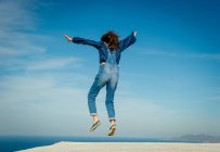 Заднього вигляду дівчина, стрибки середині повітря, Санторіні, Kikladhes, Греція — стокове фото