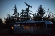Camper van in rural setting at dusk, illuminated by fairy lights — Stock Photo