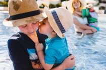 Сім'я у відкритому басейні, молодий хлопчик тримає молодшого брата — стокове фото