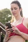 Young female runner on stairway looking at smartphone — Stock Photo
