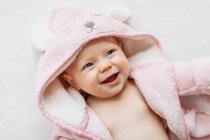 Portrait of smiling baby girl in hooded towel — Stock Photo