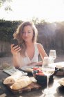 Retrato de mulher jovem usando smartphone à mesa — Fotografia de Stock