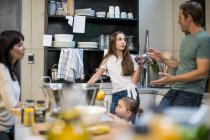 Муж и жена разговаривают с дочерью на кухне, малышка тянется за лимонами — стоковое фото