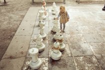 Жіночий малюк грає з гігантськими шахами в парку — стокове фото