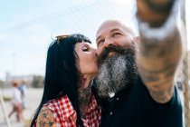 Mature hipster woman kissing boyfriend while taking selfie — Stock Photo
