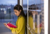 Side view of young woman writing in notepad — Stock Photo