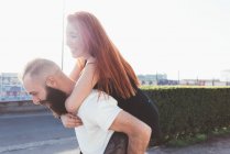 Мужчина дает рыжеволосой женщине на спине — стоковое фото