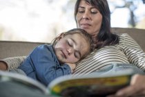 Mädchen schläft, während Mutter Buch liest — Stockfoto