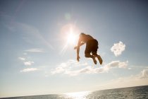 Visão de ângulo baixo de homem jovem pulando — Fotografia de Stock