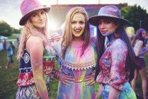 Retrato de três jovens mulheres cobertas de pó de giz colorido no festival — Fotografia de Stock