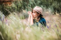 Mulher de chapéu sentado em grama longa — Fotografia de Stock