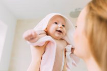 Madre sosteniendo bebé hija envuelta en toalla - foto de stock