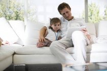 Father using digital tablet with baby girl on sofa — Stock Photo