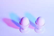 Due uova in coppe d'uovo su sfondo viola — Foto stock