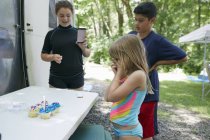 Tre bambini in piedi vicino al tavolo con torte — Foto stock