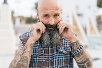 Portrait of mature male hipster pulling his moustache — Stock Photo