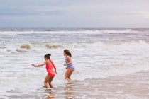 Две девочки, играющие на океанских волнах, остров Дофин, Алабама, США — стоковое фото
