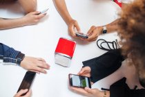 Група молодих друзів, які сидять за столом, використовуючи смартфони, середній розділ — стокове фото