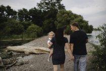 Rear view of couple strolling on beach with male toddler son, Lake Ontario, Canada — Stock Photo