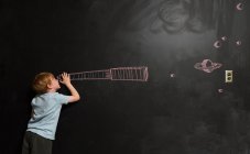 Junge blickt durch imaginäres Teleskop auf Tafel gezeichnet — Stockfoto