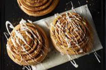 Cinnamon Rolls drizzled with Icing on wax paper — Stock Photo