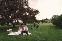 Romantico giovane coppia avendo rosa champagne picnic nel parco al tramonto — Foto stock