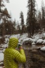 Männlicher Wanderer trinkt Kaffee am verschneiten Waldfluss, Mammutbaum-Nationalpark, Kalifornien, USA — Stockfoto