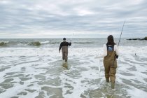 Young fishing couple in waders in sea — Stock Photo