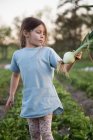 Молода дівчина на фермі, тримаючи свіжоспечену цибулю — стокове фото