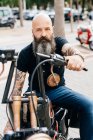 Portrait of mature male hipster astride motorcycle in parking lot — Stock Photo