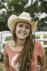 Портрет молодої жінки на відкритому повітрі, в ковбойському капелюсі, посміхаючись — стокове фото