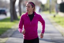 Vista frontale della giovane donna che fa jogging sulla strada — Foto stock