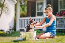 Chica lavado perro en cubo al aire libre - foto de stock