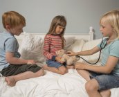 Bambini che giocano con stetoscopio e peluche — Foto stock