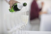 Kellner, der Champagner in Sektgläser schüttet, Nahaufnahme — Stockfoto