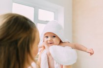 Mãe segurando bebê filha envolto em toalha — Fotografia de Stock