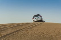 Off road vehicle driving over top of desert dunes, Dubai, United Arab Emirates — Stock Photo