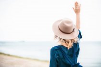 Жінка стоїть на пляжі з рукою в повітрі — стокове фото