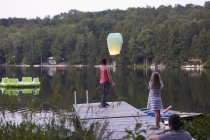 Girls releasing sky lantern and woman photographing event — Stock Photo