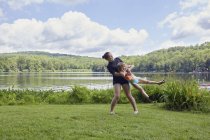 Dos chicas divirtiéndose en la hierba cerca del lago - foto de stock