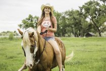 Retrato de una joven cabalgando a caballo - foto de stock