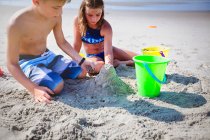Due bambini che giocano con la sabbia sulla spiaggia — Foto stock