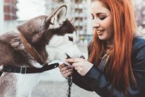 Red haired woman stroking dog — Stock Photo