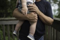 Seção média de homem carregando filho criança na varanda — Fotografia de Stock