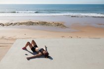 Молода жінка, лежачи на спині на пляжі, Carcavelos, Lisboa, Португалія, Європа — стокове фото