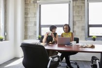 Two women using laptop at meeting room table — Stock Photo
