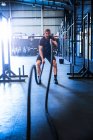 Мужчина тренируется в спортзале, используя боевые веревки — стоковое фото