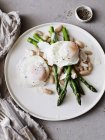 Poached eggs with asparagus on white plate, close-up — Stock Photo
