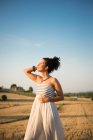 Середня доросла жінка, що стоїть на полі і насолоджується сонячним сяйвом — стокове фото